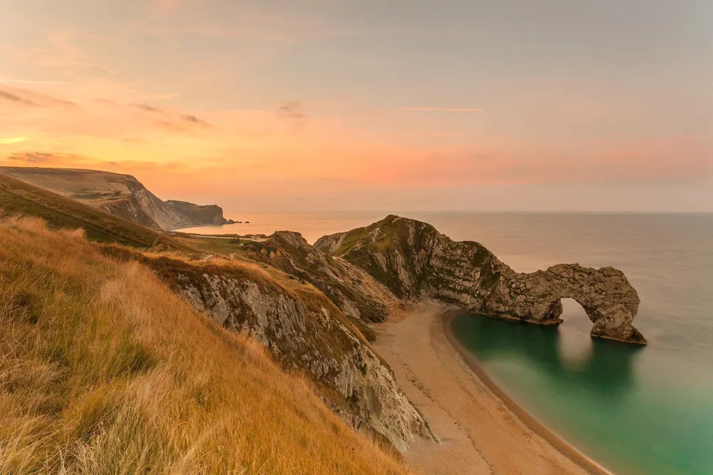 Sunset at Durdle Door, a natural rock formation on the coast, home of Wild England. 