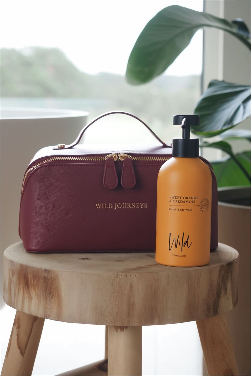 Wild Atelier Special Edition Leather Travel Case sat on stool with bottle of Sweet Orange and Cardamom Hand and Body Wash
