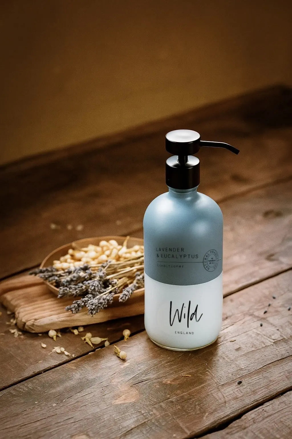 Wild England Almost Perfect natural lavender and eucalyptus conditioner 475ml bottle next to dried lavender on a rustic wooden surface