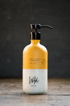 Wild England sweet orange and cardamom natural hand and body lotion 475ml on rustic wooden surface