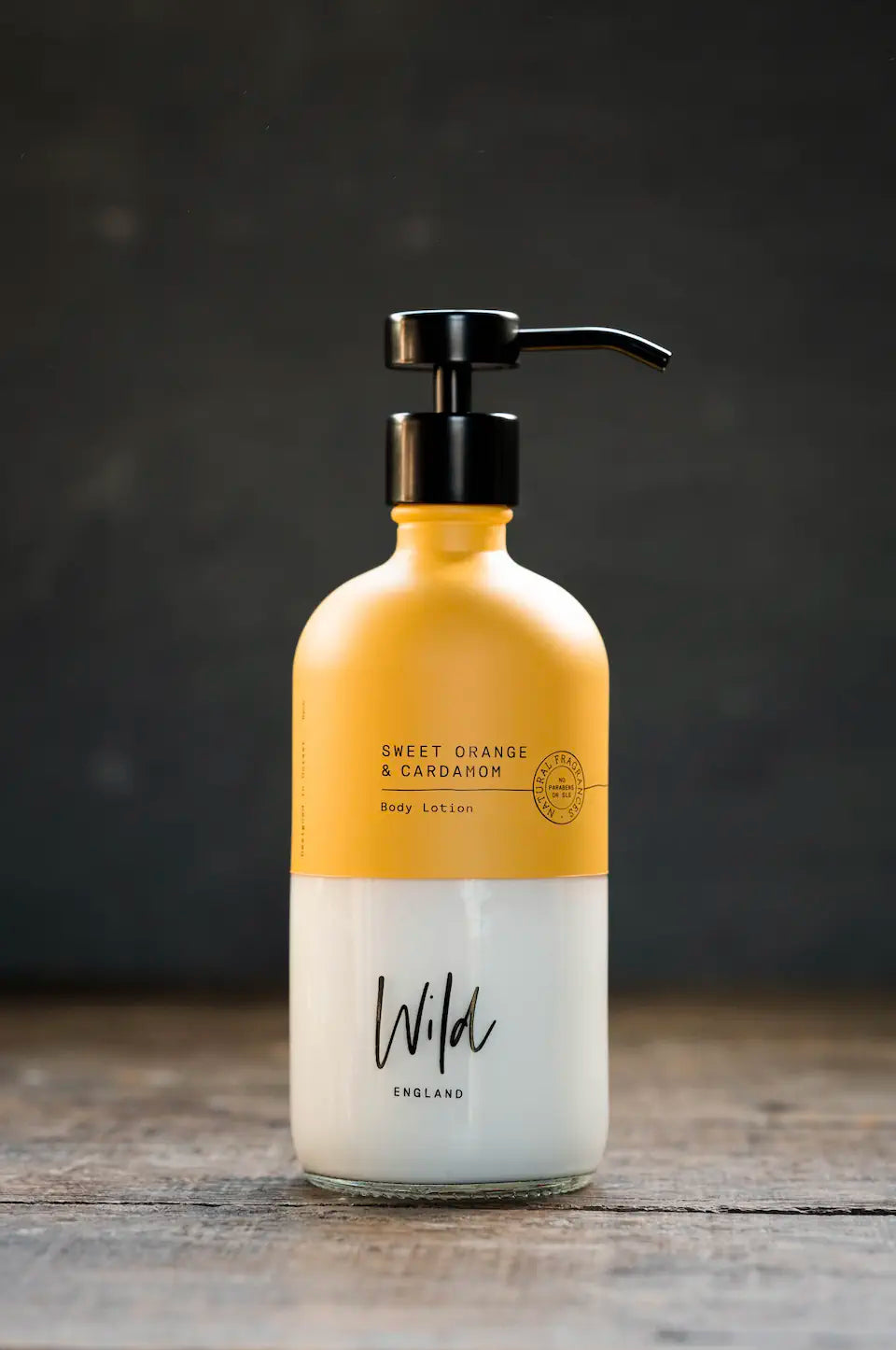 Wild England sweet orange and cardamom natural hand and body lotion 475ml on rustic wooden surface