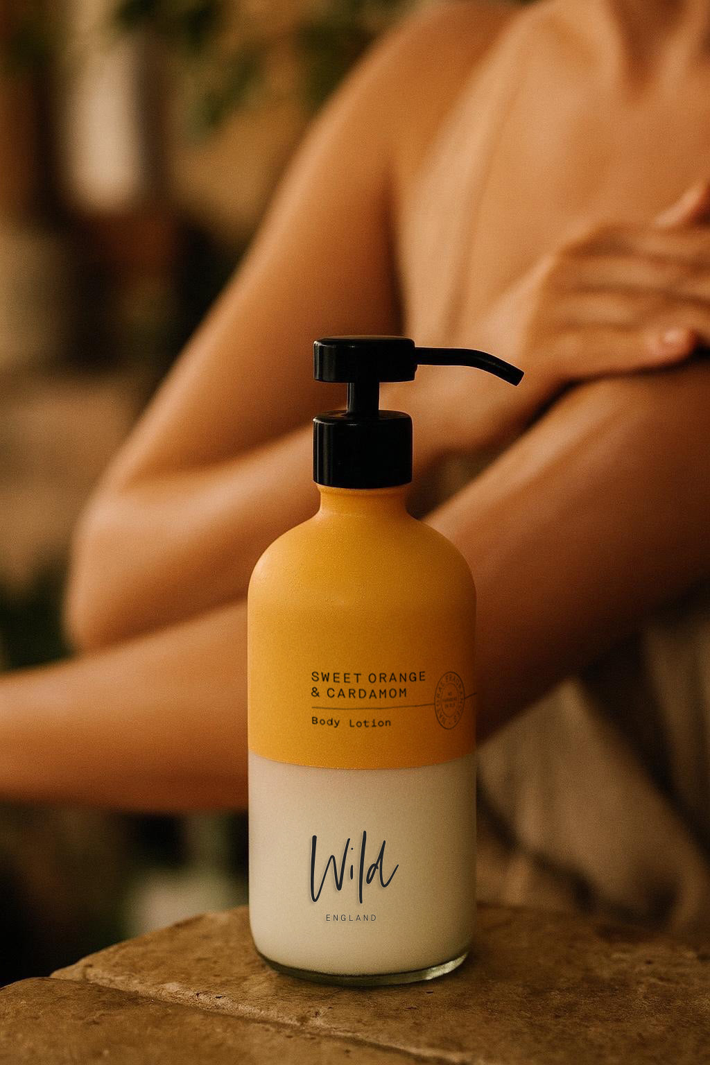Wild England sweet orange and cardamom natural hand and body lotion 475ml applied to arm by model